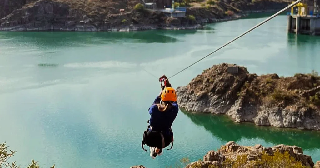 Turista practicando tirolesa sobre el lago Los Reyunos en San Rafael, Mendoza.